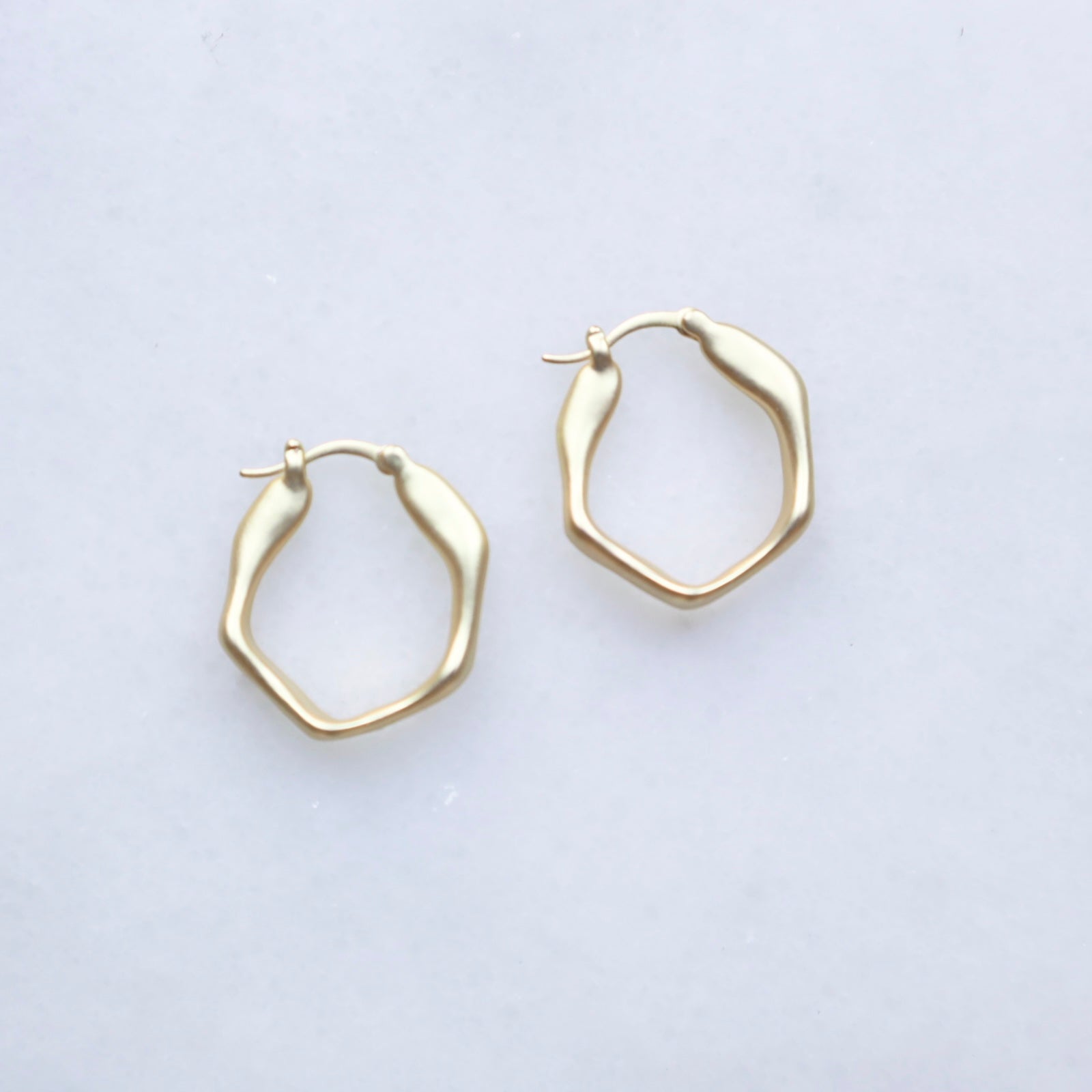 Gold hoop earrings on a light gray background
